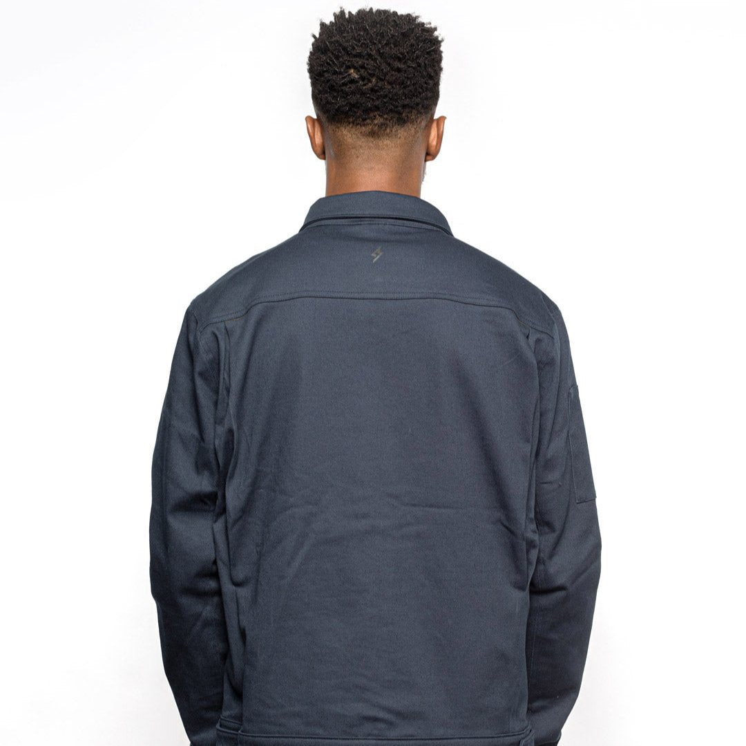 Back view of Male model wearing Anvil Chore Jacket in midnight colorway. @color_midnight