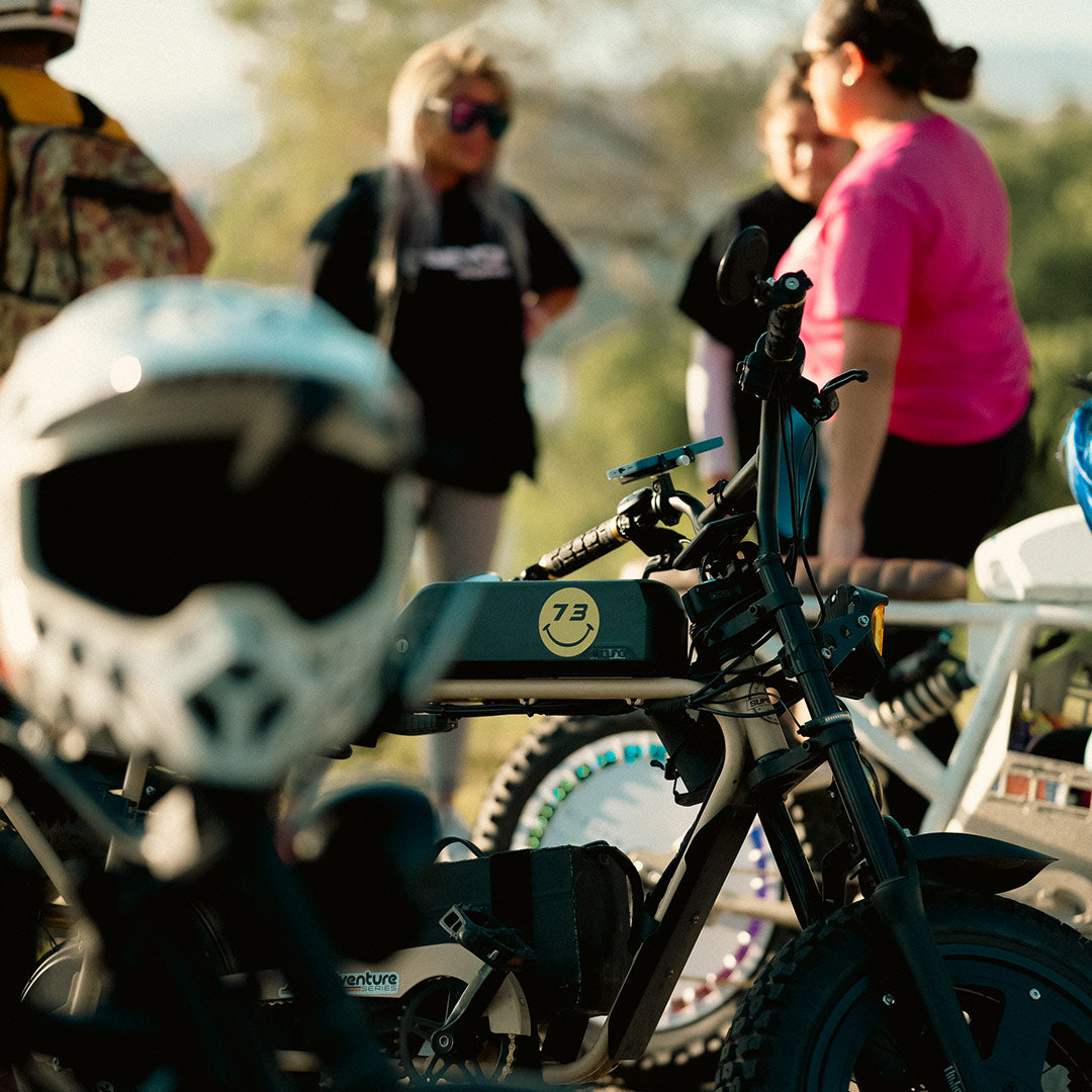 helmet in foreground and ebikes in background with three females and one male standing
